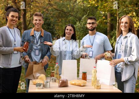 Porträt von Freiwilligen, die Lebensmittel am Tisch im Park packen Stockfoto