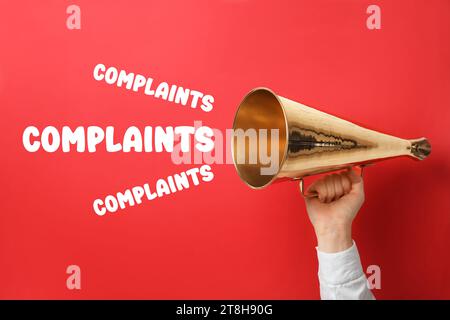 Mann mit Retro-Megaphon auf rotem Hintergrund, Nahaufnahme. Wörter Beschwerden, die vom Gerät ausgegeben werden Stockfoto