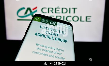 Mobiltelefon mit Website des französischen Finanzdienstleisters Crédit Agricole S.A. vor dem Logo. Fokussieren Sie sich oben links auf der Telefonanzeige. Stockfoto