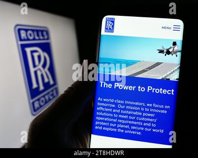 Person mit Smartphone und Website des britischen Luftfahrtunternehmens Rolls-Royce Holdings plc vor dem Logo. Konzentrieren Sie sich auf die Mitte des Telefondisplays. Stockfoto