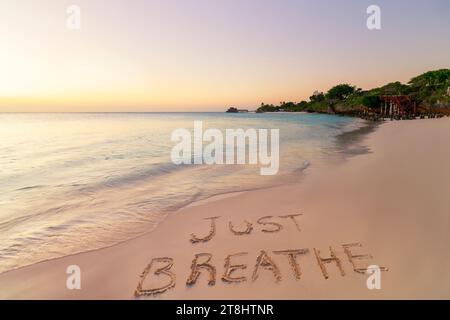 Handgeschrieben, atmen Sie einfach am Sandstrand bei Sonnenuntergang, entspannen und Sommerkonzept, Sansibar, Kendwa Beach, Tansania. Stockfoto