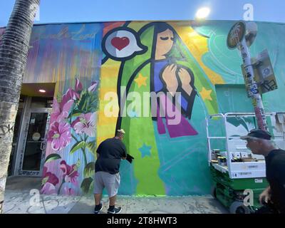 Miami, Florida, USA. Januar 2023. Ein Graffiti-Künstler auf der Arbeit. Wynwood ist die Heimat der höchsten Konzentration an Graffiti Street Art in den USA. Wandmalereien aus aller Welt zeigen ihr Talent an Wänden mit überlebensgroßen Meisterwerken. Wynwood ist bekannt für seine vielen farbenfrohen Wandmalereien und eines der beliebtesten Viertel der Stadt. Das Wynwood Walls ist ein Freiluftmuseum, in dem große Werke einiger der weltweit bekanntesten Straßenkünstler ausgestellt werden. In den umliegenden Straßen wurden Lagerhäuser mit Handwerksbrauereien und ausgefallenen Kunstgalerien umgebaut. Eine hippe junge Menschenmenge besucht den Chic der Nachbarschaft Stockfoto