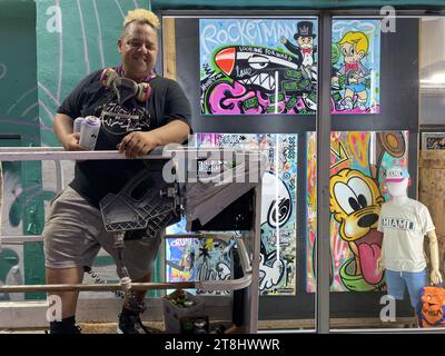 Miami, Florida, USA. Januar 2023. Ein Graffiti-Künstler auf der Arbeit. Wynwood ist die Heimat der höchsten Konzentration an Graffiti Street Art in den USA. Wandmalereien aus aller Welt zeigen ihr Talent an Wänden mit überlebensgroßen Meisterwerken. Wynwood ist bekannt für seine vielen farbenfrohen Wandmalereien und eines der beliebtesten Viertel der Stadt. Das Wynwood Walls ist ein Freiluftmuseum, in dem große Werke einiger der weltweit bekanntesten Straßenkünstler ausgestellt werden. In den umliegenden Straßen wurden Lagerhäuser mit Handwerksbrauereien und ausgefallenen Kunstgalerien umgebaut. Eine hippe junge Menschenmenge besucht den Chic der Nachbarschaft Stockfoto