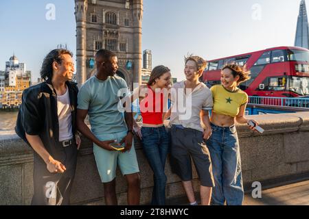 Multirassische Gruppe glücklicher junger Freunde, die sich in London City zusammenschließen - multiethnische Teenager-Studenten treffen sich und haben Spaß in Tower Bridge Gegend, Großbritannien - Konzept Stockfoto