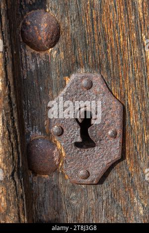 Antikes, rostiges metallisches Schlüsselloch an alter Holztür, Nahaufnahme Stockfoto