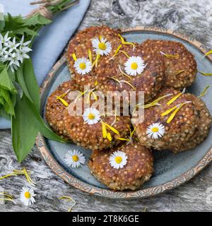 selbstgemachte Kräuterpasteten mit wildem Knoblauch auf einem Teller, dekoriert mit Gänseblümchen Stockfoto