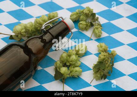 Gewöhnlicher Hopfen (Humulus lupulus), Flaschenbier und Hopfenkegel auf bayerischer Flagge, Deutschland, Bayern Stockfoto