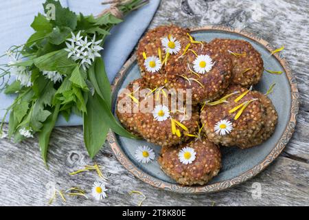 selbstgemachte Kräuterpasteten mit wildem Knoblauch auf einem Teller, dekoriert mit Gänseblümchen Stockfoto