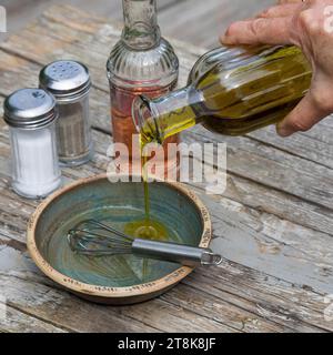 selbstgemachtes Dressing für Kräutersalat, Essig, Öl, salz und Pfeffer werden in einer Schüssel gerührt Stockfoto