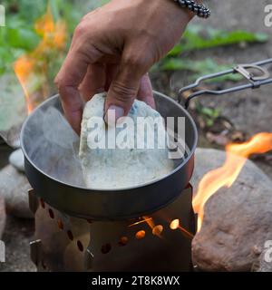 Bannockherstellung, wird auf offenem Feuer gebacken, Brotteig wird gebildet und in einer Pfanne auf einem Campingkocher gebacken, Serienbild 5/5 Stockfoto