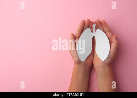 Kind, das Papier der menschlichen Lungen auf rosa Hintergrund hält, Draufsicht. Leerzeichen für Text Stockfoto