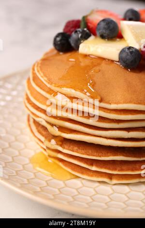 Leckere Pfannkuchen mit frischen Beeren, Butter und Honig auf dem Tisch, Nahaufnahme Stockfoto