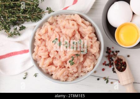 Flache Lagenkomposition mit frischem rohem Hackfleisch und Thymian auf weißem Holztisch Stockfoto