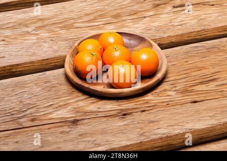 Mandarinen in einer Holzschale auf hölzernem Hintergrund. Stockfoto