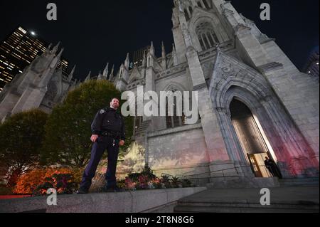 New York, USA. November 2023. Ein NYPD-Offizier steht über dem Treppeneingang zur St. Patrick's Cathedral während der feierlichen Enthüllungsfeier der Saks Fifth Avenue nur einen Block entfernt, New York, NY, 20. November 2023. (Foto: Anthony Behar/SIPA USA) Credit: SIPA USA/Alamy Live News Stockfoto