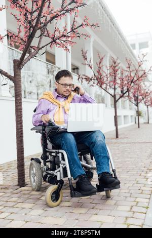 Ein Mann mit Behinderung mit Laptop und Telefon Stockfoto