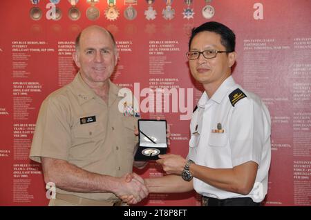 Matthew Nathan, Navy Surgeon General, und Rear ADM. Kang Wee Lee, Chief Medical Corps der Streitkräfte Singapur tauschen Geschenke aus, 25. Februar 2014. Stockfoto