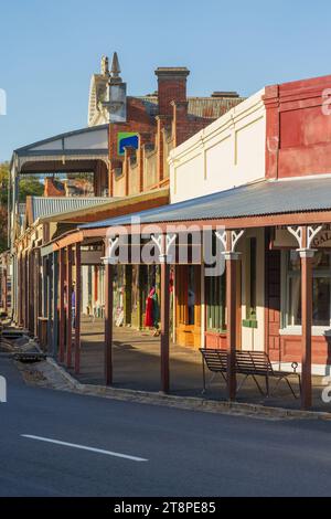 Eine historische Straßenlandschaft gesäumt von Veranden in der späten Nachmittagssonne in Maldon im Zentrum von Victoria, Australien. Stockfoto