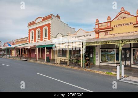 Schmiedeeiserne und kunstvoll verzierte Verandapfosten vor alten Gebäudefassaden in einer historischen Straßenlandschaft in Maldon in Central Victoria, Australien Stockfoto