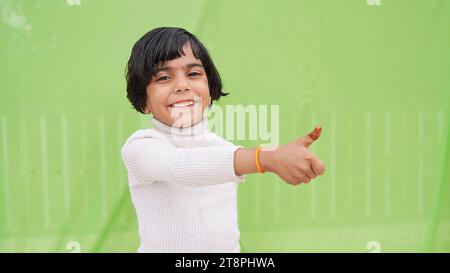 Foto des fröhlichen, glücklichen jungen Mädchens machen Finger Daumen hoch Lächeln Empfehlen Sie isoliert auf grünem Hintergrund Stockfoto