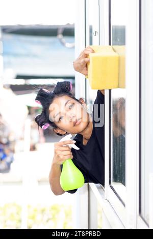 Eine junge Frau wäscht die Außenfenster in einem Wohnhaus Stockfoto