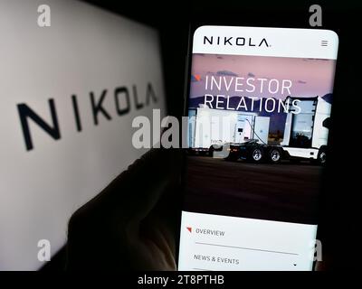 Person, die ein Handy hält, mit der Webseite des US-amerikanischen Elektrofahrzeugunternehmens Nikola Corporation vor dem Logo. Konzentrieren Sie sich auf die Mitte des Telefondisplays. Stockfoto