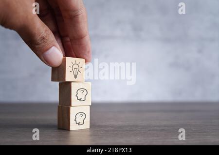 Wählen Sie Holzwürfel mit einer Glühbirne auf dem menschlichen Kopf aus. Kreative Idee, Brainstorming und Innovationskonzept. Stockfoto