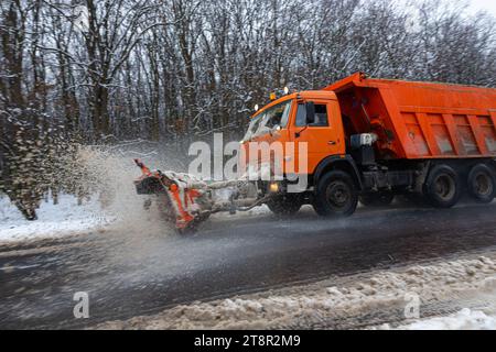 Ein großes Auto mit einem Pflug befreit die Straße von Schnee. Die Sonderausrüstung Orange Cargo kämpft im Winter mit den Elementen. Beseitigung der Auswirkungen von t Stockfoto