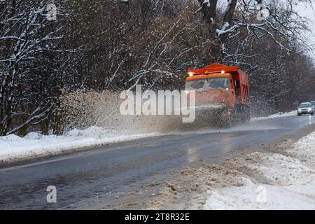 Ein großes Auto mit einem Pflug befreit die Straße von Schnee. Die Sonderausrüstung Orange Cargo kämpft im Winter mit den Elementen. Beseitigung der Auswirkungen von t Stockfoto