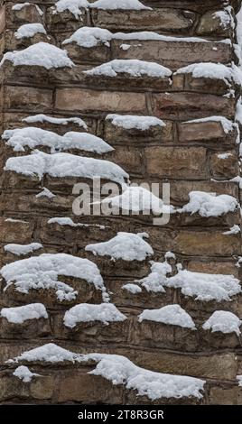 Mittelalterliche Steinmauer ist mit Schnee bedeckt, Design Hintergrund mit Platz für Text. Stockfoto