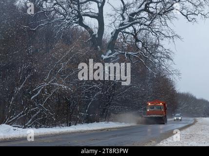 Ein großes Auto mit einem Pflug befreit die Straße von Schnee. Die Sonderausrüstung Orange Cargo kämpft im Winter mit den Elementen. Beseitigung der Auswirkungen von t Stockfoto