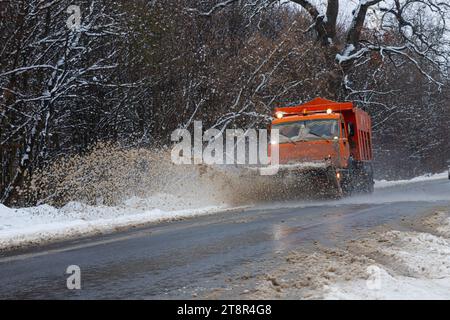 Ein großes Auto mit einem Pflug befreit die Straße von Schnee. Die Sonderausrüstung Orange Cargo kämpft im Winter mit den Elementen. Beseitigung der Auswirkungen von t Stockfoto