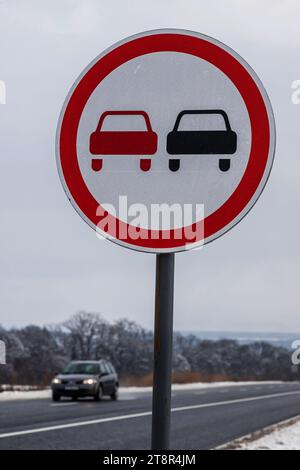 Verschneite Straße mit Verkehrsschild Überholverbot. Straße auf dem Land. Stockfoto