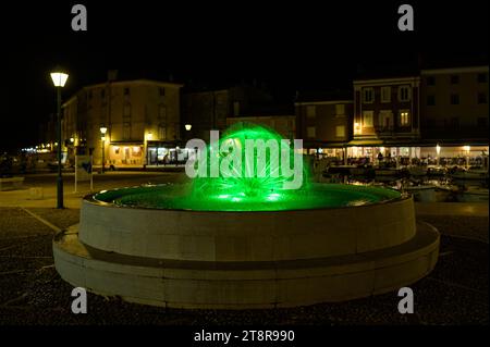 Cres, Kroatien - 8. April 2023: Detail eines Brunnens auf dem Hauptplatz in der Nähe des Hafens in Cres mit farbigen Lichtern Stockfoto