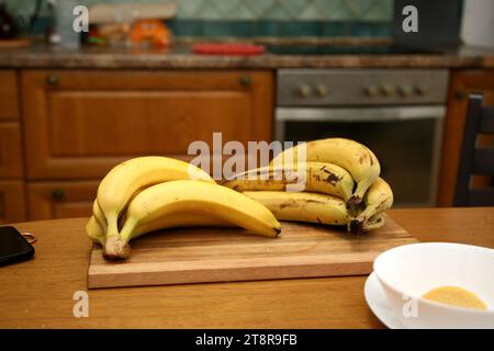 Bananen liegen auf einem soliden Holztisch. Süße reife Bananen mit gelber Haut Stockfoto