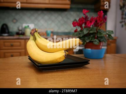 Bananen liegen auf einem soliden Holztisch. Süße reife Bananen mit gelber Haut Stockfoto