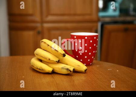 Bananen liegen auf einem soliden Holztisch. Süße reife Bananen mit gelber Haut Stockfoto