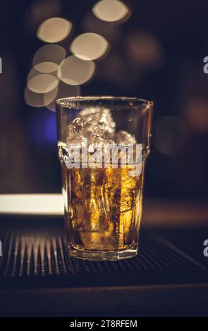 Ein Glas Whiskey auf den Eisfelsen auf einer schwarzen Stegmatte Stockfoto