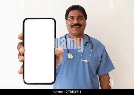 Indischer Doktor Mit Blauen Scrubs Zeigt Großes Smartphone Mit Leerem Bildschirm Stockfoto