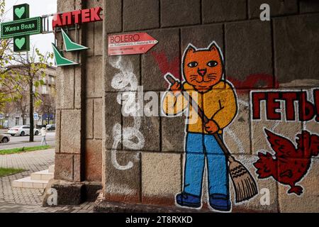 An der Wand eines Gebäudes in Zaporischzhia ist ein patriotisches Katzengraffiti (geschrieben – „Beat it“) zu sehen, das vom Team der LBWS CAT UKRAINE hergestellt wurde. LBWS CAT UKRAINE ist ein Team von Künstlern aus Odesa City, die patriotische Straßenkunst mit verschiedenen Bildern von Katzen in Kriegszeiten kreieren. Die Künstler sagen, dass sie Katzen ausgewählt haben, weil dies eines der inoffiziellen Symbole ihrer Heimatstadt Odesa ist. Ihor Matroskyn und Andrii Bilyi kommen beide aus Odesa und sind Teil der LBWS CAT UKRAINE, die derzeit aus fünf Personen besteht, von denen die meisten lieber anonym bleiben. Die Künstler verwenden ihre eigenen Mittel für ihre Stockfoto