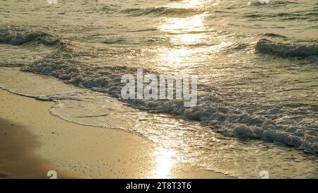 Nahaufnahme sanfte Wellen übersäten den Sandstrand, Sommer Hintergrund. Wunderschöne Meereswellen mit Schaum von goldener Farbe isoliert. Stockfoto
