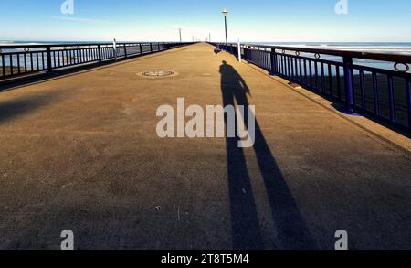 In den Schatten gelangten zwei New Brighton Piers in New Brighton, Neuseeland. Der erste Pier in Holzbauweise wurde am 18. Januar 1894 eröffnet und am 12. Oktober 1965 abgerissen. Der heutige Betonpfeiler wurde am 1. November 1997 eröffnet. Es ist eine der Ikonen von Christchurch, Neuseeland Stockfoto