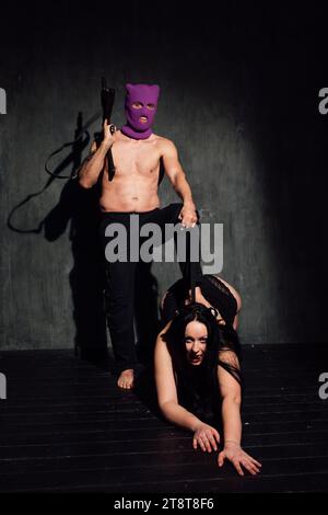 Ein Mann, der eine Maske mit einem Maschinengewehr trägt, mit einer Frau im Kragen Stockfoto