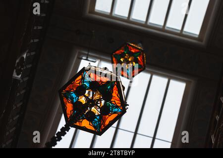 Unter dem Deckenfenster hängen Vintage-Kronleuchter aus farbenfrohem Buntglas Stockfoto