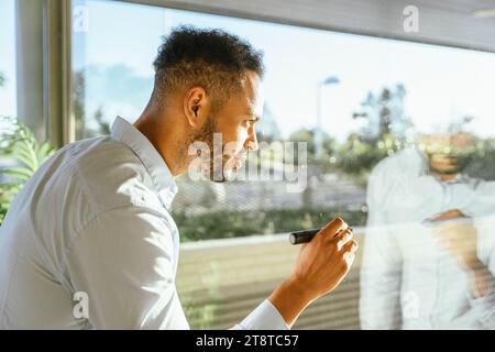 Professioneller Geschäftsmann, der Ideen an das Fenster schreibt, während er an einem Startup-Projekt arbeitet. Business- und Brainstorming-Konzept. Stockfoto
