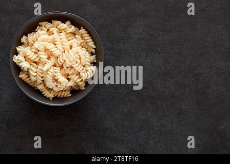 In der Schüssel gekochte Fusilli-Pasta auf dunklem Hintergrund, Draufsicht, Platz zum Kopieren von Text. Stockfoto