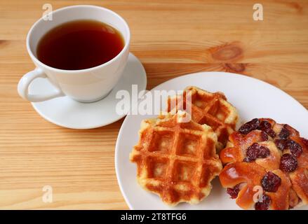 Belgische Waffeln mit einer Tasse heißem Tee auf Holztisch Stockfoto