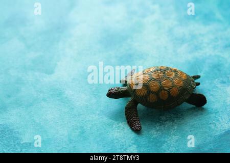 Grüne Spielzeugschildkröte auf einem hellblauen Aquarellhintergrund Stockfoto