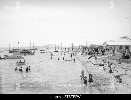 Szene am Bucklands Beach, Auckland, Neuseeland, Sommerszene am Bucklands Beach mit schwimmenden Menschen und am Strand. Boote und Häuser sind sichtbar. Hindman's Store ist auf der rechten Seite. Die Insel Rangitoto ist in der Ferne zu sehen. P Anfang der 1900er Jahre Stockfoto