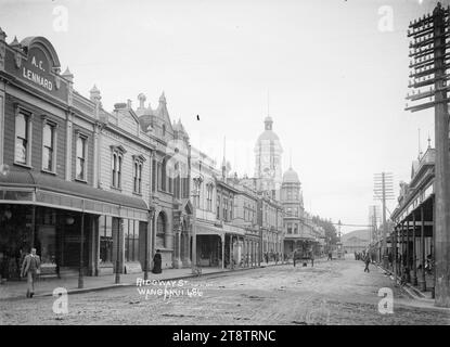 Blick auf die Ridgway Street, Wanganui, Neuseeland, Blick auf die Ridgway Street, Wanganui, Neuseeland, Blick auf das Postamt, mit dem Watt Fountain an der Kreuzung mit der Victoria Avenue in der mittleren Distanz. Der Uhrturm der Post ist in der Mitte links zu sehen, die Straße ist von Geschäften gesäumt, und es gibt einen Pferdewagen, der von der Kamera wegfährt. Vor Dezember 1908, als der Brunnen an einen anderen Ort verlegt wurde, um Platz für die neue Straßenbahn zu schaffen, die im Dezember 1908 offiziell eröffnet wurde Stockfoto